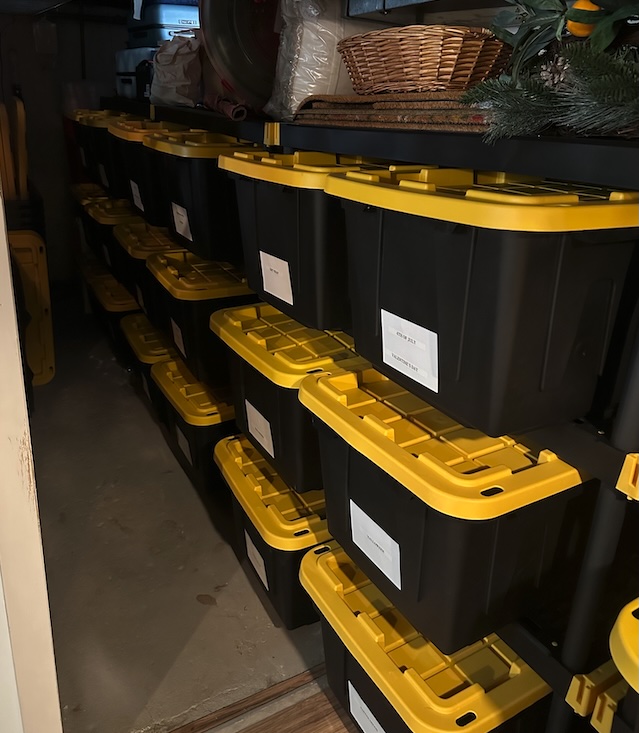 Stacked rows of labeled black-and-yellow storage bins arranged on basement shelving in an Ocean County, New Jersey home, organized by OCD Organized to bring clear structure and easy access to stored items.